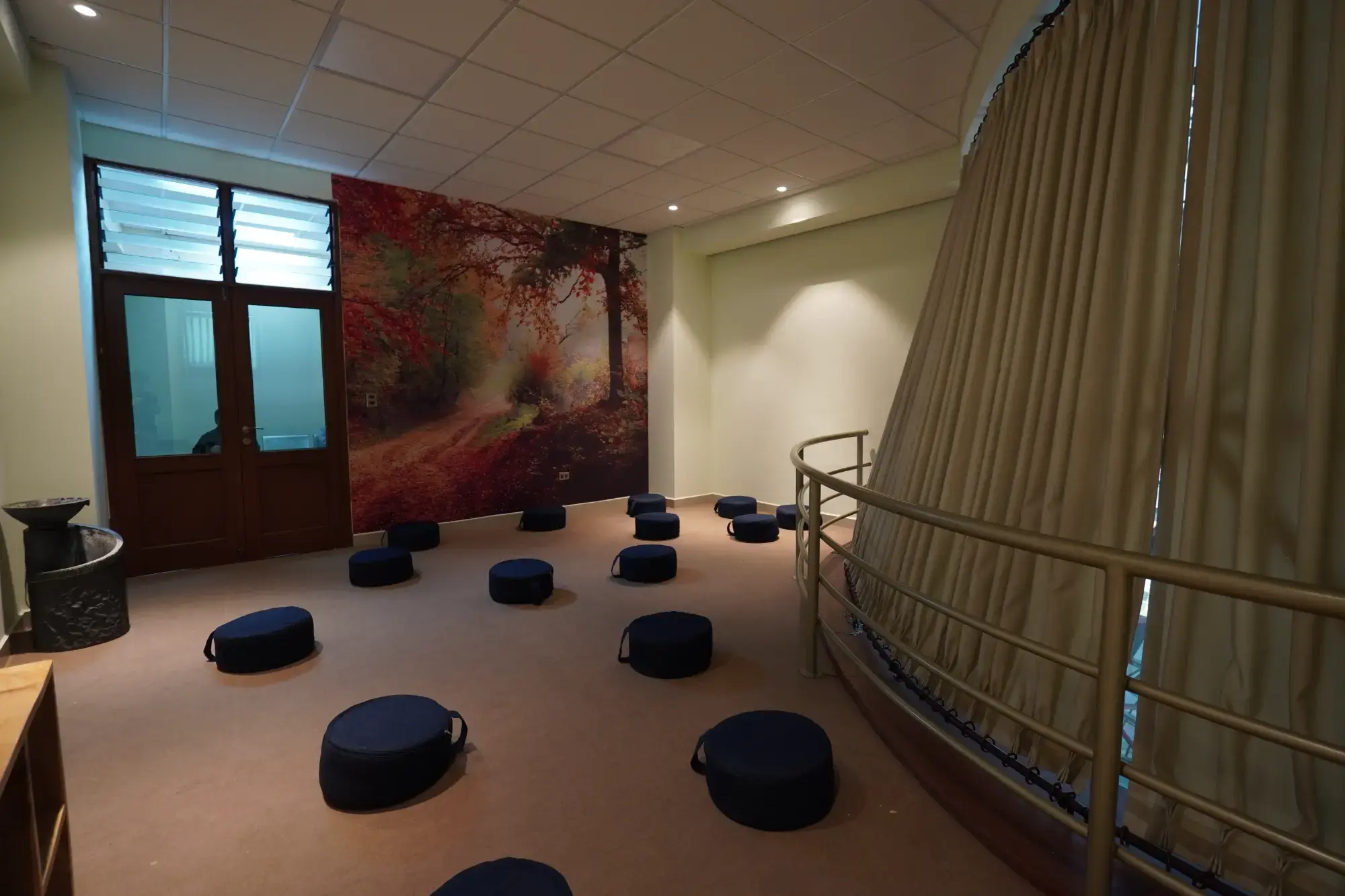 Sala de meditación del Campus Túpac Amaru con cojines y mural de bosque