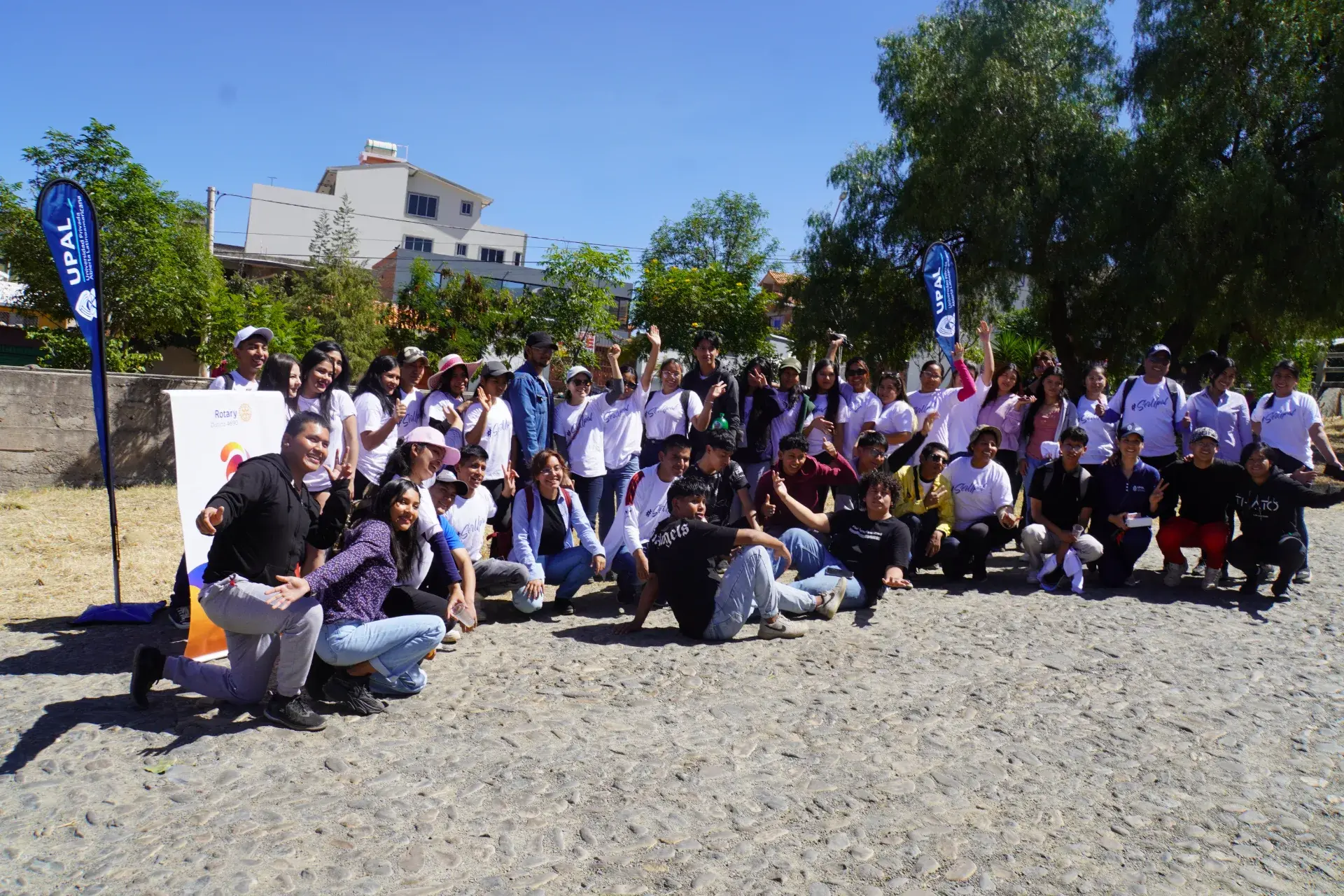 Grupo de estudiantes y voluntarios de la UPAL con la camiseta #SerUpal junto a un banner de Rotary