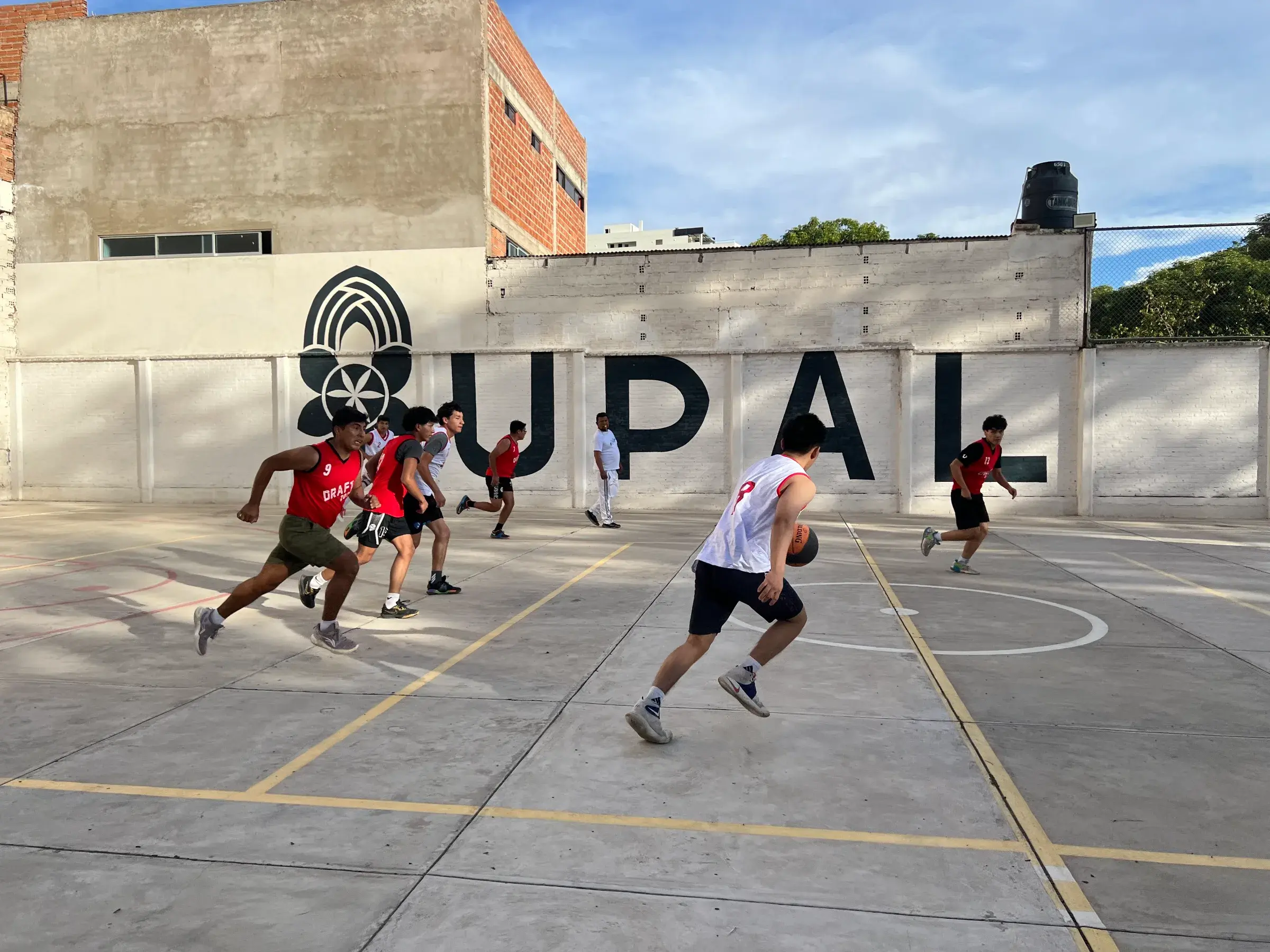 Estudiantes del club de baloncesto de la UPAL jugando un partido frente al mural UPAL