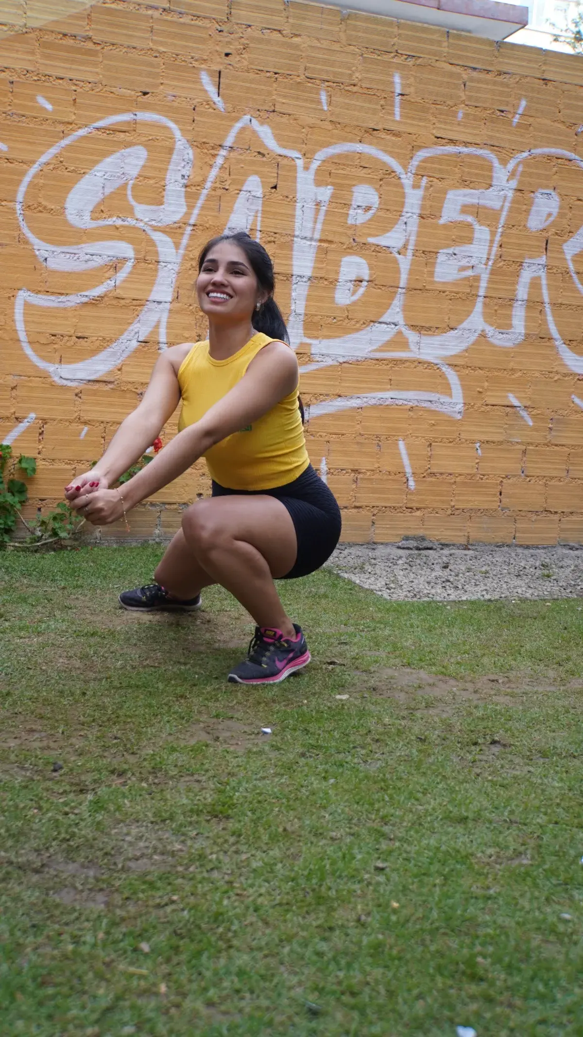 Estudiante de la UPAL en posición de juego de voleibol frente al mural Saber